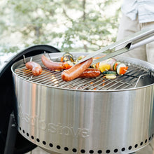 Load image into Gallery viewer, Solo Stove Grill Ultimate Bundle - Side View View Of The Grill In Use - Charcoal Lit With Food Cooking On The Grill Surface As Grill Utensils Are Used