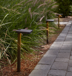 Hamlin LED Path Lights Three Bronze Lights on Display to the Side of a Walkway, In A Garden